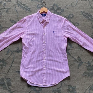 Rosa randig skjorta från Ralph Lauren - Säljer en slim fit skjorta från Ralph Lauren i rosa och vitt med tunna ränder. Nypris 1800kr