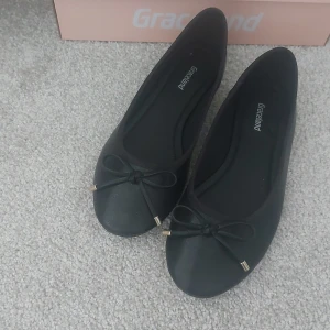 Svarta ballerinaskor från Graceland - Svarta ballerinaskor från Graceland med rund tå och en rosett framtill med små guldfärgade detaljer. Använda endast en gång. Köpta för 299kr 💕💕