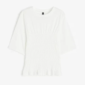 smockad topp - Superfin vit topp med smockad midja och lätt volangkant nertill. Modellen har rund halsringning och halv-långa ärmar, perfekt för en clean och stilren look. Enkel att matcha med både jeans och kjol. Använd sparsamt och i ny skick.