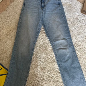 Ljusblå raka jeans med rå kant - Snygga ljusblå jeans med rak passform och rå, fransad kant nertill. Klassisk femficksmodell i mjukt denimtyg, perfekta för en avslappnad look. Passar dig som gillar enkel och tidlös stil.