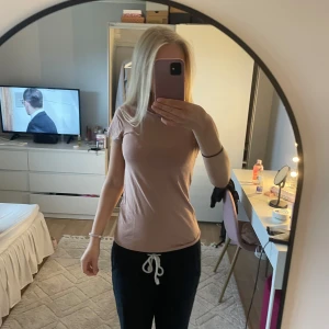 Beige t-shirt från KappAhl XS - En basic beige t-shirt från KappAhl i ekologisk bomull. Modellen är figurnära med korta ärmar och rund halsringning. Perfekt för en clean och enkel stil, lätt att matcha med allt