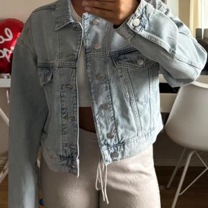 Ljusblå jeansjacka från - Säljer en ljusblå jeansjacka från Bik Bok i storlek XS. Jackan har klassisk krage, silverfärgade knappar framtill och två bröstfickor med lock. Snygg croppad modell som passar perfekt till vardagslooken.
