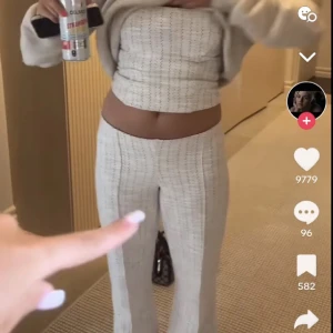 Beige bandeau tubtopp i tweed - Säljer en beige bandeau tubtopp i tweed-look med diskret rutigt mönster. Toppen är axelbandslös och croppad, perfekt att styla med matchande byxor eller kjol. Ger en clean och trendig vibe med sin strukturerade form och ljusa färgton.