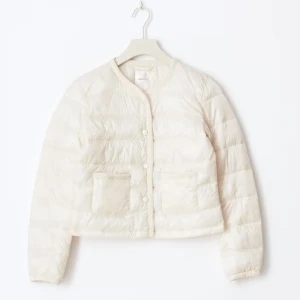 Vit croppad dunjacka med knappar - Snygg vit dunjacka i croppad modell med rund halsringning, knäppning framtill och två fickor fram. Fint skick och oanvänd