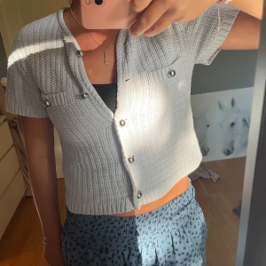 Kortärmad kofta  - Kort stickad kofta från H&M med silvriga knappar framtill. Koftan har korta ärmar och en ribbad struktur som ger en trendig look. Som ny!