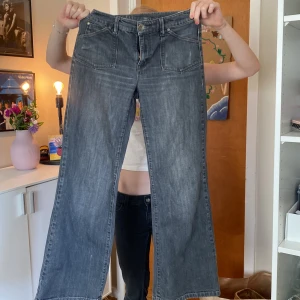 Grå wide jeans från KappAhl, stl 36 - Säljer ett par gråa jeans från KappAhl i storlek 36. De har breda ben, stora framfickor och snygga bakfickor med knappdetalj. Jeansen har en cool tvättad look och är perfekta för dig som gillar en avslappnad stil.
