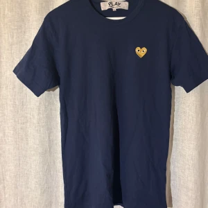 Mörkblå Comme des Garçons T-shirt. Strl L - Mörkblå t-shirt från Comme des Garçons. Tröjan är i L men sitter som M. Är i mycket bra skick.