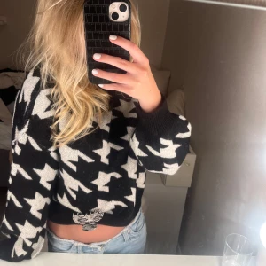 Svartvit stickad tröja med hundtandsmönster - Säljer en svart och vit stickad tröja med stort hundtandsmönster. Tröjan har en loose passform, rund halsringning och långa ärmar. Perfekt statement-piece för dig som gillar att sticka ut med din stil.