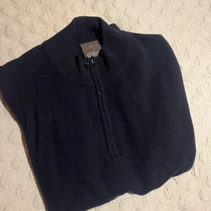 Mörkblå kashmirtröja Oscar Jacobson - Snygg mörkblå stickad kashmirtröja från Oscar Jacobson med half zip och hög krage. Tröjan har lång ärm och ribbade muddar för en clean look. Perfekt för dig som gillar stilrena och mjuka plagg med premiumkänsla. 8/10 skick