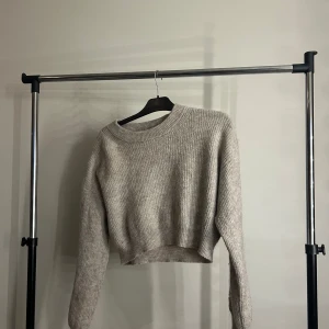 Beige croppad stickad tröja Lindex - Supermysig beige stickad tröja från Lindex i croppad modell. Tröjan har rund halsringning, långa ärmar och ribbade muddar. Perfekt för lager-på-lager och chill dagar. Enkel att matcha med jeans eller kjol.
