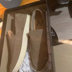 Beige loafers i mocka från Matinique - Snygga beige loafers i mocka med vit platt sula. Skorna har en stilren och minimalistisk design utan snörning, perfekt för dig som gillar en clean look. Bekväm innersula och klassisk rund tå gör dem lätta att matcha till olika outfits. Märke Matinique, nypris, 1899