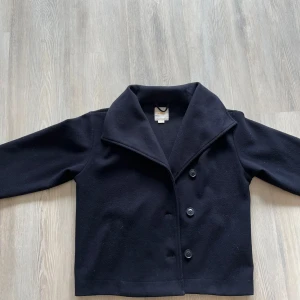 Marinblå höst kappafrån Gina Tricot - Klassisk marinblå skepparkavaj från Gina Young med bred krage och tre knappar framtill. Jackan har rak passform och är Perfekt för dig som gillar en stilren och tidlös look.