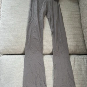 Grå bootcut byxor från Nelly XXS - Säljer ett par grå bootcut byxor från Nelly i stretchigt och mjukt material. Byxorna har hög midja med en bred linning som kan vikas ner och en figurnära passform upptill som går ut i vida ben. Perfekta för en chill och trendig look. är i xxs men passar xs och s. aldrig använda 