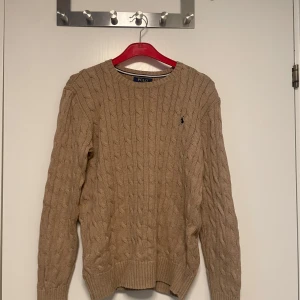 Stickad tröja Polo Ralph Lauren - Säljer en beige kabelstickad tröja från Polo Ralph Lauren. Köpt i Usa så lite större i storleken. Funkar som S 