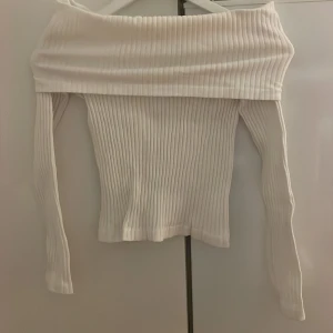 Vit ribbad offshoulder topp Zara - Säljer en vit ribbad offshoulder topp från Zara. Toppen har långa ärmar och en bred, vikt kant över axlarna.