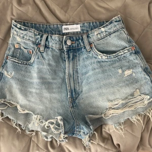 Blå slitna jeansshorts från Zara - Snygga ljusblå jeansshorts från Zara med normal midja och fransiga kanter. 