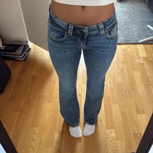 Blå bootcut jeans från Perfect Jeans - Snygga blå bootcut jeans från Perfect Jeans med låg midja och klassisk femficksdesign. Jeansen har en lätt tvättad look, raka ben med lätt utsvängning och coola detaljer på bakfickorna. Perfekta för dig som gillar en avslappnad men trendig stil. Säljer då dom aldrig kommit till användning. Ny pris 399