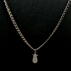 Silverhalsband med droppformad pärla - Stilrent halsband i silverfärg med en kedja och ett hängsmycke i form av en vit, droppformad pärla. Hängsmycket har en liten stjärndetalj upptill som ger en unik touch. Perfekt för dig som gillar minimalistiska smycken med en twist.