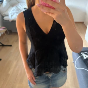 Svart ärmlös linnetopp med v-ringning - Snygg svart ärmlös linnetopp med djup v-ringning och lätt utsvängd nederkant. Toppen har en enkel och stilren design. Är i storlek xs men har krympt lite i tvätten 💘 Har knappt använt 