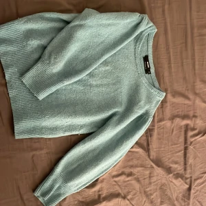 Ljusblå stickad tröja från Bik Bok - Mysig ljusblå stickad tröja från Bik Bok i ullblandning. Tröjan har rund halsringning, långa ärmar och breda ribbade muddar vid ärmslut och nederkant. Perfekt för lager-på-lager under kyliga dagar.