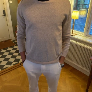 Beige stickad tröja - En stilren beige stickad tröja med rund halsringning och ribbade muddar. Tröjan är från Jack & Jones. Model är 183cm 75kg