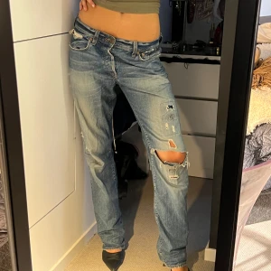 Levis 501 ljusblå - Ljusblå Levis 501 jeans med coola slitningar och hål på benen.. Klassisk femficksmodell, raka ben och låg midja. Jeansen är i bomull och har en loose passform som ger en skön och trendig look. DÖR för dessa byxor men just denna färg på jeans använder jag aldrig längre, så dags för någon annan att få rocka dessa. Jag är S och de sitter perfekt på mig (173cm)