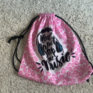 Rosa leopardmönstrad gympåse - Snygg gympåse med rosa leopardmönster och svart text med 'Please don't stop the music' samt illustration av hörlurar. Använt 1-2gg så inga defekter.