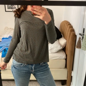 Brunprickig långärmad tröja - Aldrig använd!!!!!     Säljer en långärmad tröja i mjukt material med brunt och blått prickigt mönster. Tröjan har en avslappnad passform och rund halsringning, perfekt till jeans eller kjol. Skön och stilren för dig som gillar unika prints.