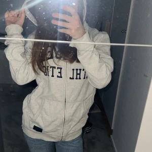 Ljusgrå hoodie från L.O.G.G. med tryck - Ljusgrå hoodie från L.O.G.G. med svart tryck framtill. Tröjan har dragkedja, huva och två fickor. Tillverkad i mjuk bomullsmix, perfekt för chill dagar. Klassisk passform och långa ärmar.💕