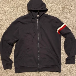Moncler Hoodie XL - Säljer en väldigt fin och bra bevarad Moncler Hoodie i storlek XL. (Storlekarna är betydligt mindre, skulle mer säga att hoodien är storlek L). Den är väldigt fin och i ett bra skick. Ställ gärna frågor om du undrar något!