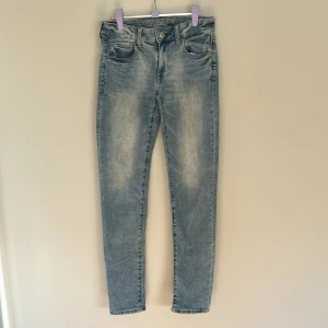 Ljusblå skinny jeans från American Eagle - Snygga ljusblå skinny jeans från American Eagle med klassisk femficksdesign och diskret slitning framtill. Jeansen har normalhög midja och är tillverkade i mjukt denim med stretch för extra komfort. Perfekta till sneakers eller boots.