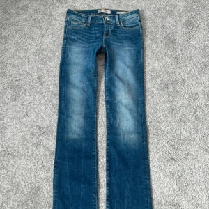 Blå bootcut jeans från Guess - Snygga blå jeans från Guess med bootcut passform och låg midja.   Ny utan prislapp  Midjemått rakt över:32 Midjemått mätt runtom:68 Innerbenslängd: 80 Stuss:37 Lär:19 Gren:17 Benöppning:19