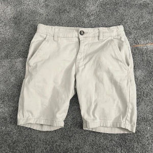 Beige shorts från 157 Lee Star - Snygga beige shorts från 157 Lee Star med klassisk passform. De har två sidofickor fram, två bakfickor och hällor för bälte. Perfekta för varma dagar och enkla att matcha med allt. Gjorda i mjuk bomull för skön känsla hela dagen.