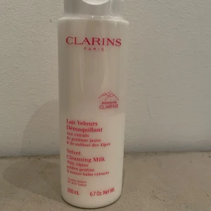 Clarins Velvet Cleansing Milk 200ml - Clarins Velvet Cleansing Milk är en rengöringsmjölk med extrakt av alpina örter som gentiana och citronmeliss. Kommer i en vit plastflaska med röd text, 200 ml. Passar alla hudtyper och tar bort smink på ett skonsamt sätt.