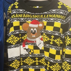 AIK jultröja XS med musmotiv - Gul och svart stickad jultröja från AIK i storlek XS. Tröjan har ett stort broderat musmotiv med tomteluva och AIK-halsduk, samt snöflingor och rutigt mönster. Perfekt för dig som vill sticka ut på julfirandet och visa AIK-stolthet. Sjukt skön å lite extra snygg inför jul😉 perfekt skick! Finns heller inte kvar att köpa.