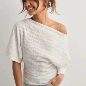 Vit offshoulder topp med boatneck - Säljer en vit trendig offshoulder topp med snygg struktur och lös passform. Toppen har korta ärmar och en lätt ribbad känsla i tyget. Perfekt för dig som gillar en avslappnad men trendig stil. Har används fåtal gånger, säljer pga inte kommer till användning längre. Köpt för 299kr! 🩷