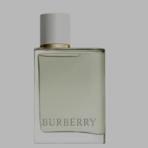 Burberry parfym med vit kork - Stilren parfym från Burberry i en transparent glasflaska med ljusgrön vätska. Flaskan har en vit, rund kork med gulddetalj och Burberry-loggan ingraverad framtill. Perfekt för dig som gillar klassisk och elegant design.