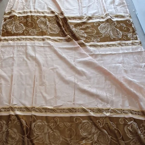 Gardin - Säljer en stor vanlig gardin i beige och brunt med vackert blommönster. Gardinens kanter har en fin fransdetalj som ger en extra touch av stil. Längd: 248 cm och Bredd: 141cm. (Det är en gardin men vet inte vilken slags men den är inte så tunn)