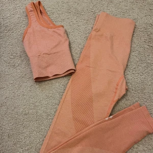 Rosa träningstopp och tights från Lager 157 - Sportig rosa topp och tights från Lager157 med ribbade detaljer och bred resår. Toppen har en snygg, croppad passform och är tillverkad i stretchigt syntetmaterial som passar perfekt till träning. Storlek Xs/S