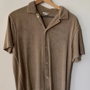 Frottéskjorta från East West - Snygg skjorta i mjuk frotté från East West. Skjortan har korta ärmar, klassisk krage och knäppning framtill. Perfekt för en avslappnad och trendig look. Enkel att matcha med jeans eller shorts.