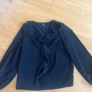 Svart blus/tröja med volang på framsidan - Jättesnygg svart blus/tröja från shein som har volangdetaljer på framsidan av den. Tröjan är enkel att styla och den har aldrig kommit till användning så skicket på den är jättebra💕💕