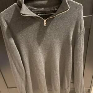 Grå half zip tröja Jack & Jones - Mörkgrå långärmad tröja från Jack & Jones i storlek S. Tröjan har en snygg half zip-dragkedja vid kragen och är tillverkad i mjukt material som känns skönt mot huden. Perfekt för lager-på-lager och enkel att matcha med jeans eller chinos.🍾