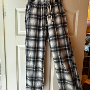Rutig mjukisbyxa flanell från 157  - Mysiga mjukisbyxor från 157 i svartvitt rutigt mönster. Byxorna har resår och snörning i midjan för skön passform. Perfekta för chill dagar hemma eller när du vill vara extra bekväm. Tillverkade i mjukt material som känns skönt mot huden. Säljer då dom aldrig används.