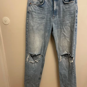 Ljusblå ripped jeans från Gina Tricot - Säljer ett par ljusblå jeans från Gina Tricot med slitna hål över knäna. Jeansen raka ben och hög midja. 