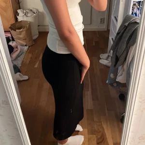 Svart långkjol i tight passform - Säljer en svart långkjol med tight passform. Kjolen är enkel och stilren, perfekt att matcha med crop tops eller stickade tröjor. Den har en rak siluett och sitter snyggt över höfterna. Passar dig som gillar minimalistisk och clean stil.