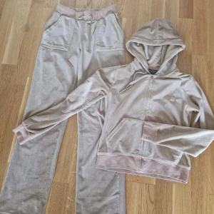 Beige Juicy Couture Set - Set från Juicy Couture i fint använt skick. Stl  S på tröjan och stl Xs på byxorna. Hittar inget att anmärka på. Katt finns i hemmet, tvättar inte parfymfritt. 