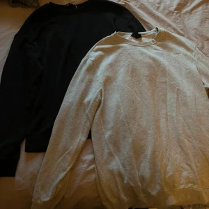 Grå och svart basic sweatshirt - Två stilrena sweatshirts i grått och svart, perfekta för en clean och avslappnad look. Båda har rund halsringning och långa ärmar. Tillverkade i mjukt bomullsmaterial som är skönt mot huden. Passar perfekt till jeans eller joggers.