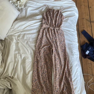 Blommig dress från H&M - Supersöt dress från H&M med smala axelband och blommigt mönster i beige, brunt, blått och rosa. Dressen har resår i midjan för en snygg passform och är perfekt för varma dagar. Lätt och luftig känsla! Den har även fickor på båda sidorna.