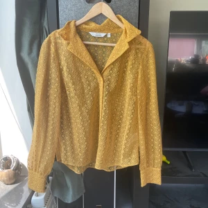 Gul spetsblus från & Other Stories - Använd en gång! Säljer en transparent gul spetsblus från & Other Stories Paris Atelier. Blusen har långa ärmar, klassisk krage och är täckt av broderade blommor. Perfekt för dig som vill sticka ut med en unik och färgglad look.