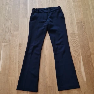 Svarta bootcut kostymbyxor BikBok - Snygga svarta kostymbyxor från BikBok i bootcut-modell. Byxorna har hällor för bälte, fickor fram och stängs med dragkedja och knapp. Perfekta för en clean och stilren look.
